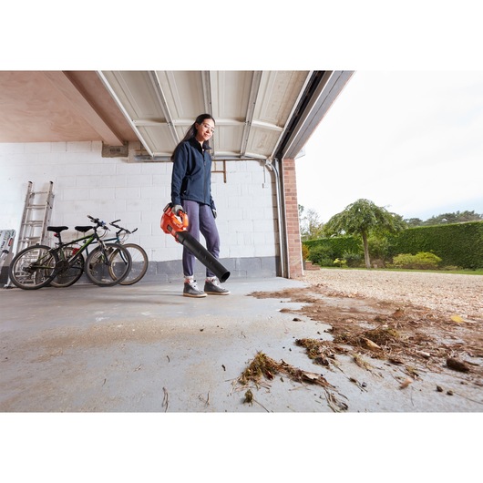 BLACKDECKER BCBL200B leaf blower used to clear garage floor, bikes and ladder in background.