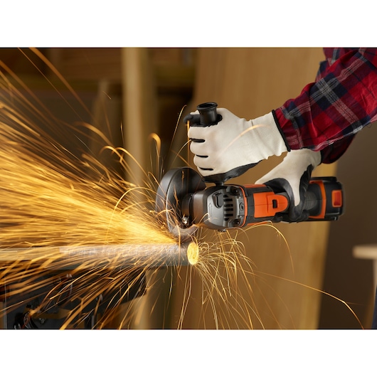 BLACKDECKER BCG720N cordless angle grinder cutting metal pipe, sparks flying, close-up view.