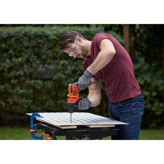BLACKDECKER BEH200 corded drill used outdoors on metal grid by person wearing gloves and goggles.