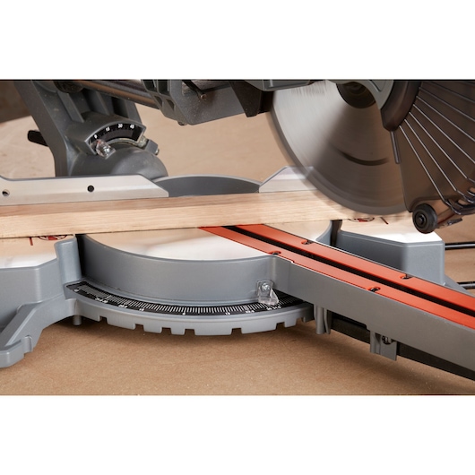BLACKDECKER BES710 miter saw side angle cutting wood, orange guide rail, silver base.
