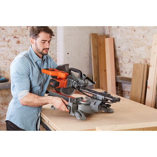 Photo of BLACKDECKER BES710 mitre saw on a workbench in a workshop, person adjusting the tool.