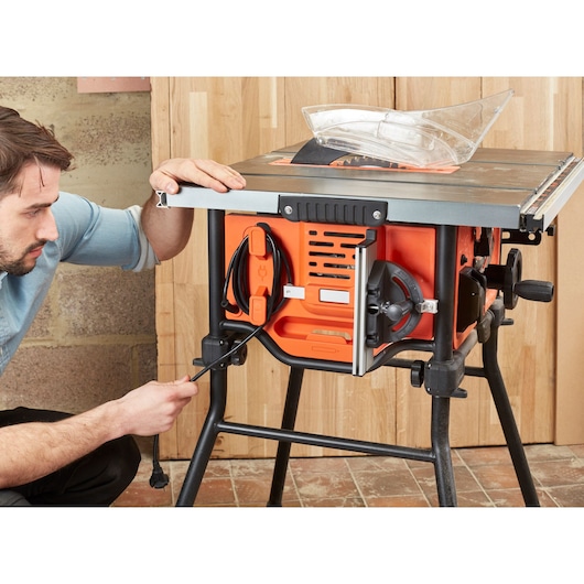 BLACKDECKER BES720 table saw on stand, side view showing orange and black housing, cord storage, adjustment knobs.
