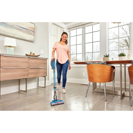 BLACKDECKER BHFE520J cordless stick vacuum cleaner used on tile floor in a modern dining room.