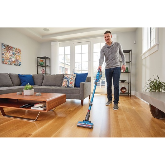 BLACKDECKER BHFE520J cordless stick vacuum in blue used on hardwood floor in modern living room