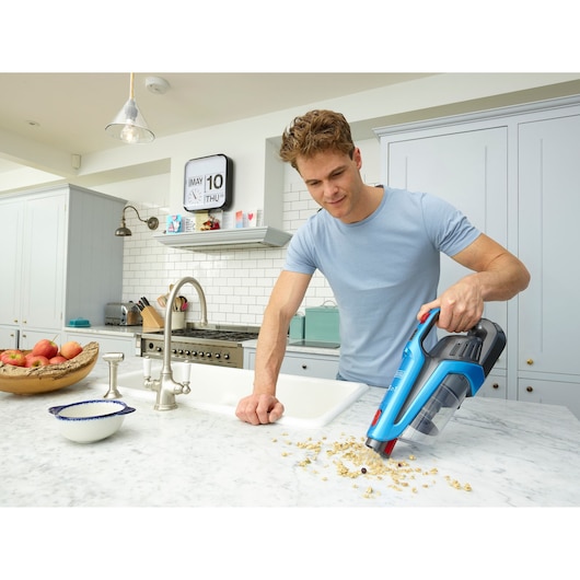 BLACKDECKER BHFE520J cordless vacuum cleaning crumbs on marble kitchen counter.