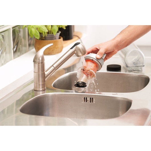 BLACKDECKER BHFEA18D1 vacuum filter being rinsed under faucet in a kitchen sink.