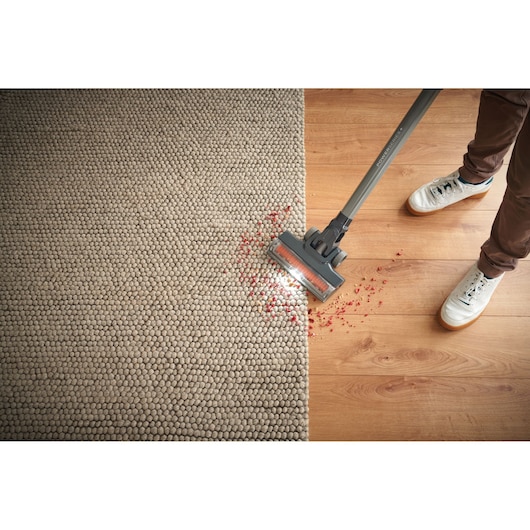 BLACKDECKER BHFEA515JB vacuum cleaner with LED head cleaning crumbs on carpet and wood floor, top view.