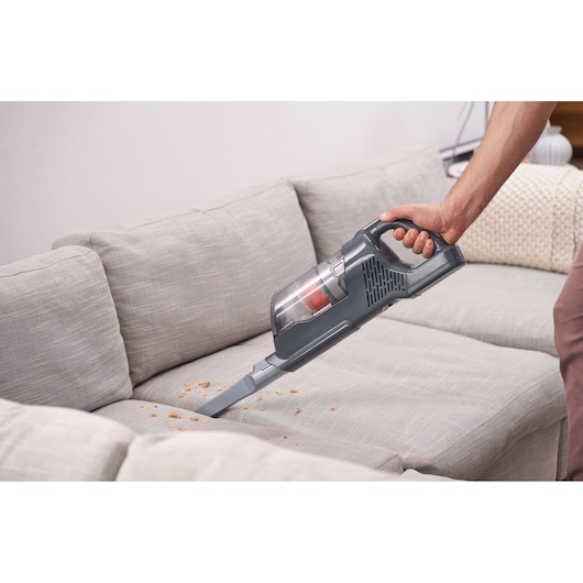 BLACKDECKER BHFEA515JB handheld vacuum cleaner removing crumbs from a light grey sofa.