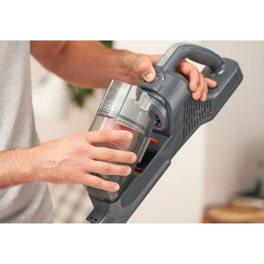 Photo of a person removing the dust container from a BLACK+DECKER cordless vacuum cleaner BHFEA515JB.