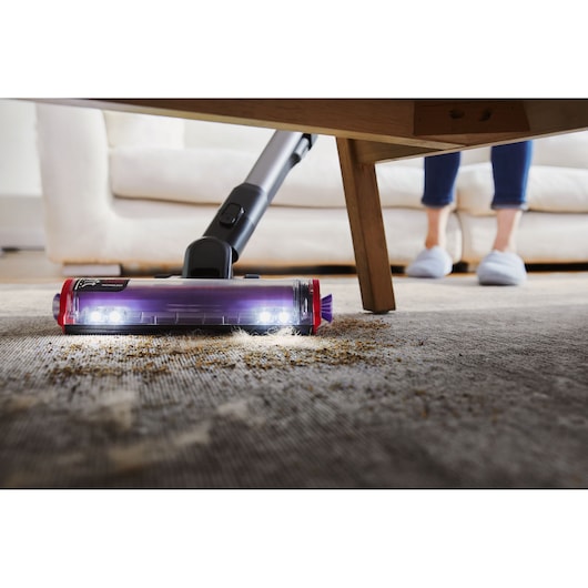 BLACKDECKER BHFEA640WP cordless vacuum cleaning under a table on a carpet with LED lights on the floor tool.