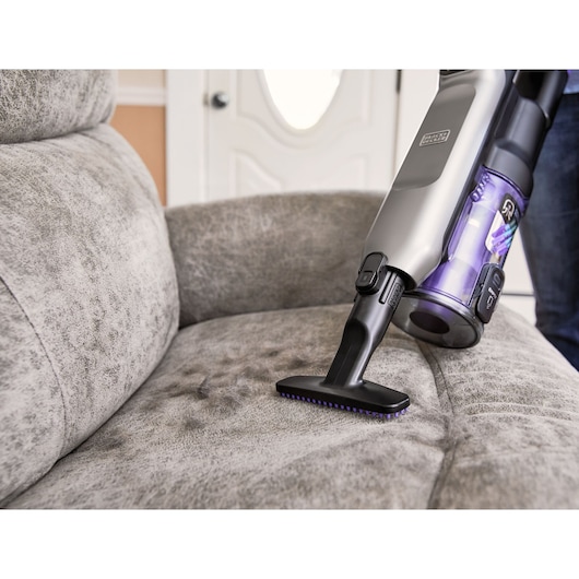 BLACKDECKER BHFEA640WP cordless vacuum cleaning gray upholstered sofa close-up.