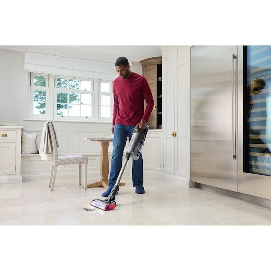 BLACKDECKER BHFEA640WP cordless stick vacuum in use cleaning dirt from light kitchen floor.