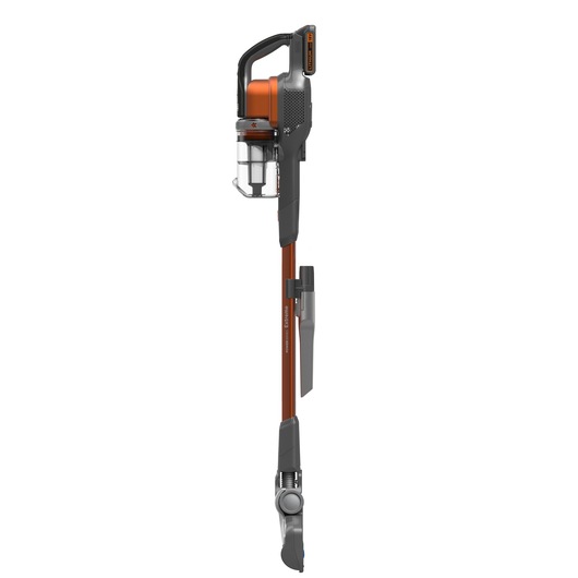 A cordless stick vacuum cleaner with orange and black accents, featuring a transparent dust container and an attached nozzle accessory, shown in a vertical position against a white background.
