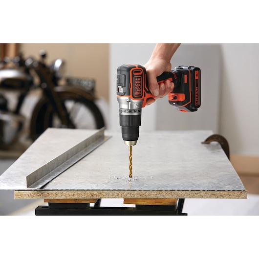 BLACK+DECKER BL188N cordless drill in use drilling into a metal sheet on a workbench.