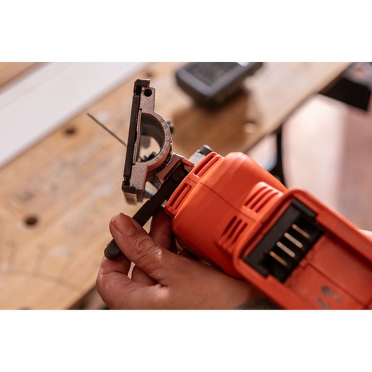 Close-up photo of BLACK+DECKER BLCJS78N jigsaw being adjusted by hand, with focus on blade and grip.