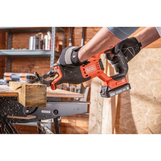 BLACKDECKER BLCR78N cordless reciprocating saw cutting wood in a workshop setting.