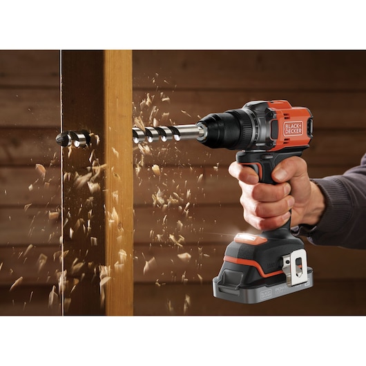 Photo of BLACK+DECKER BLD682D1 cordless drill in use drilling through a wooden beam, sawdust flying.