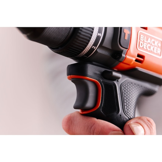 Close-up photo of BLACK+DECKER BLD683XN power drill handle and trigger in hand, showing textured black and orange grip.