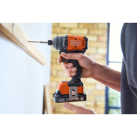 BLACKDECKER BLIM78N impact driver in use driving a screw into wood, close-up side angle.