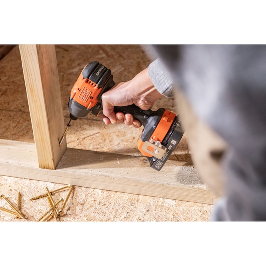 BLACKDECKER BLIM78N cordless drill in use on wooden frame, user holding tool, scattered screws visible.