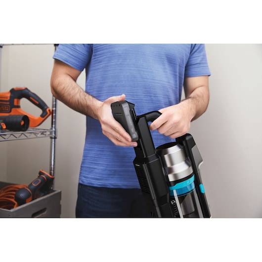 Photo of a person inserting a battery into a BLACK+DECKER BSV520BRB cordless vacuum cleaner in a garage.