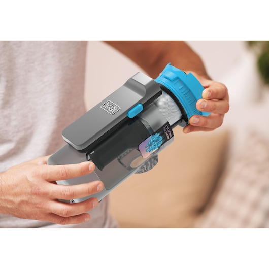 Close-up of BLACK+DECKER BSV520BRB vacuum cleaner dustbin with blue lid, shown in hand for filter cleaning.