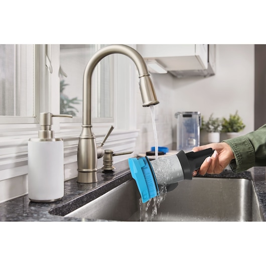 BLACK+DECKER BSV520BRB vacuum filter being rinsed under kitchen faucet, close-up view.