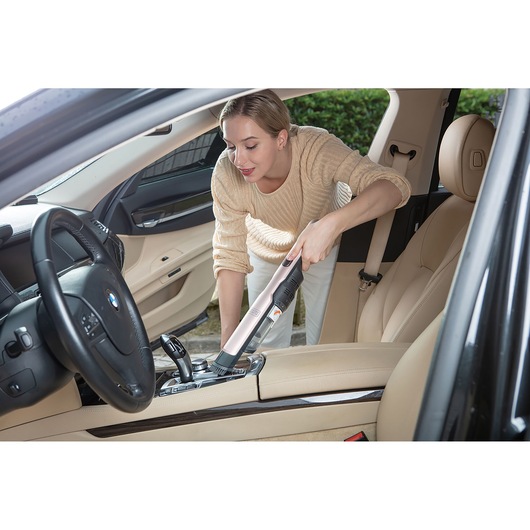 BLACKDECKER DVC320BRG handheld vacuum cleaner used for cleaning car interior, beige upholstery.
