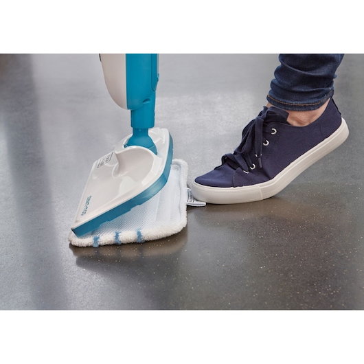 BLACKDECKER FSMH13E10 steam mop head and pad, side angle, shown being pressed down by a person’s foot.