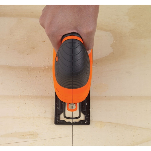 Photo of BLACKDECKER KS701E jigsaw cutting a straight line on light wood from top view.