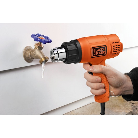 Photo of BLACK+DECKER KX1650A heat gun defrosting a frozen outdoor faucet.