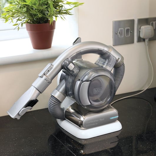 BLACK+DECKER PD1820L handheld vacuum cleaner with flexible hose on countertop, plant in background.