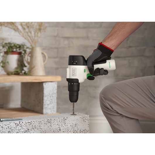 BLACKDECKER REVHD12C cordless drill in use, drilling into concrete, indoor setting.
