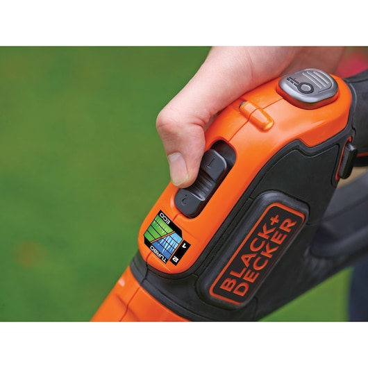 Close-up side view of BLACK+DECKER STC1840EPC cordless garden tool handle with speed control buttons and user hand.