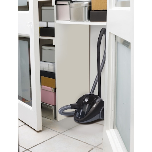 BLACKDECKER VM1450 canister vacuum cleaner in black stored in a closet with boxes and containers.