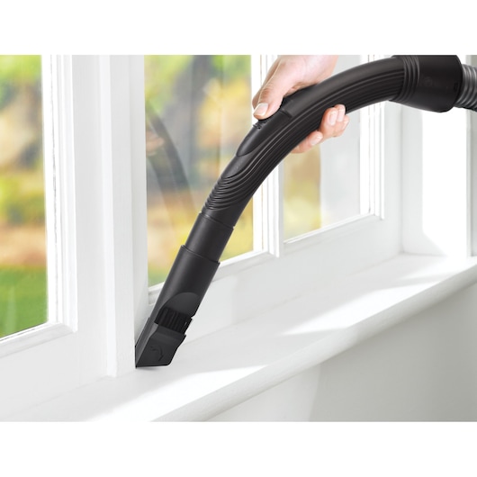 BLACKDECKER VM1450 vacuum cleaner nozzle cleaning a white window sill, close-up.