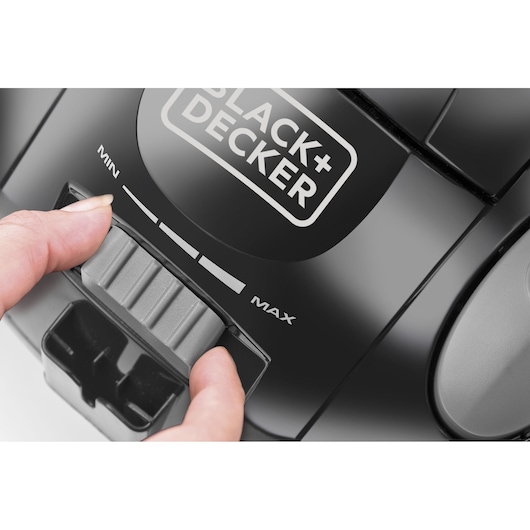 BLACKDECKER VM1450 vacuum cleaner close-up showing hand adjusting power slider on black surface.