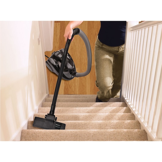 BLACKDECKER VM1450 vacuum cleaner used to clean carpeted stairs, held by a person.
