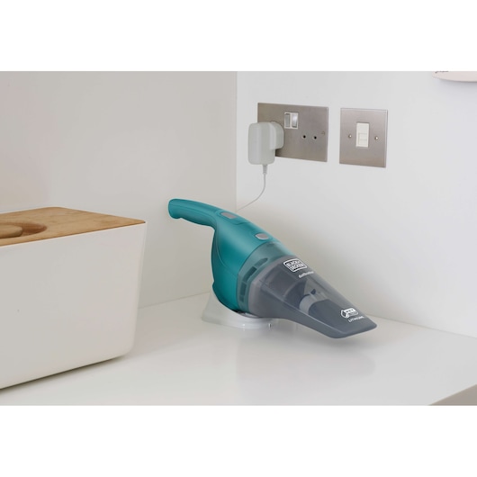 BLACKDECKER WDB115WA teal handheld vacuum charging on white countertop in kitchen corner.