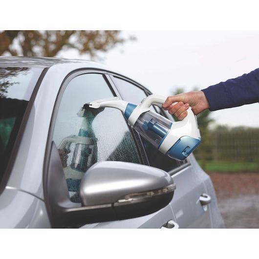 BLACK+DECKER WW100 window vacuum cleaner used on a car window, side angle, blue and white design.
