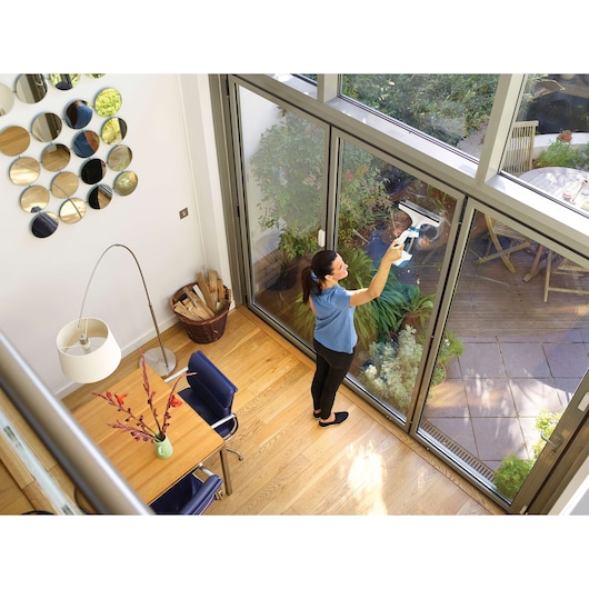 BLACKDECKER WW100 window vacuum cleaner used to clean glass doors in bright modern room.