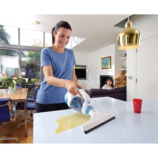 BLACKDECKER WW100 handheld wet vacuum cleaning liquid spill from table in modern kitchen.